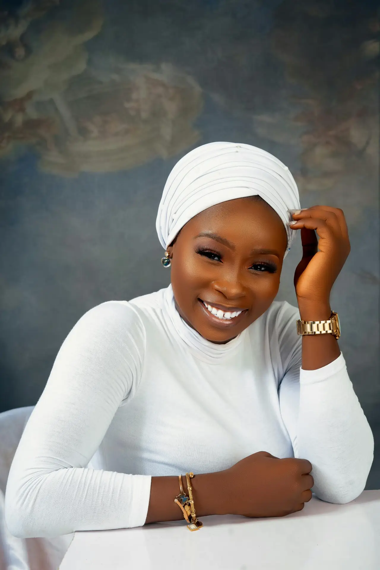 Elegant portrait of a smiling woman in a white turban and long sleeves.